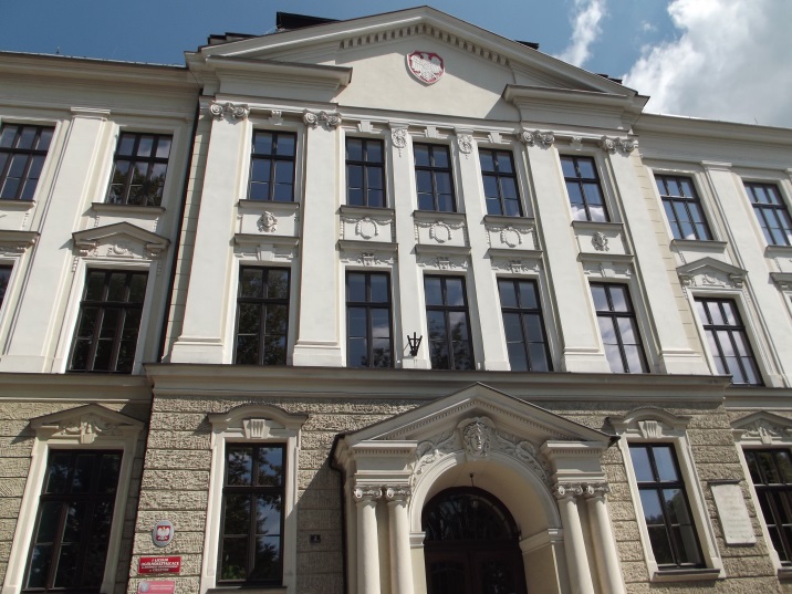 Zabytkowy budynek z jasną elewacją i kolumnowym wejściem, siedziba Starostwa Powiatowego w Cieszynie. Widoczne godło Polski oraz tablice urzędowe przy wejściu.