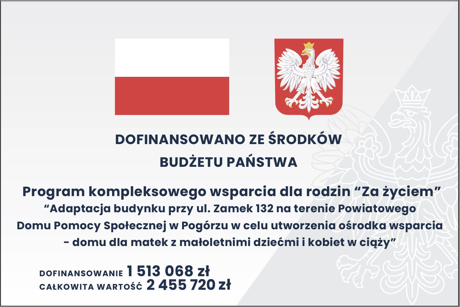 Plansza informacyjna z flagą Polski i godłem. Tekst: „Dofinansowano ze środków budżetu państwa. Program kompleksowego wsparcia dla rodzin ‘Za życiem’. Adaptacja budynku przy ul. Zamek 132 na terenie Powiatowego Domu Pomocy Społecznej w Pogórzu w celu utworzenia ośrodka wsparcia – domu dla matek z małoletnimi dziećmi i kobiet w ciąży”. Dofinansowanie: 1 513 068 zł, całkowita wartość: 2 455 720 zł.