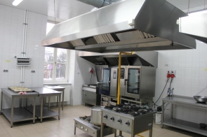 Nowoczesna pracownia gastronomiczna z profesjonalnym wyposażeniem; widoczne kuchenki gazowe, piekarniki, stoły robocze i okap w sali ZSEG w Cieszynie.