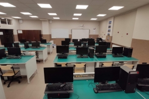 Sala w ZST w Ustroniu. Sala komputerowa z licznymi stanowiskami wyposażonymi w monitory, klawiatury i jednostki centralne; na ścianie tablice i projektor.