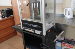 Maszyna do popcornu na metalowym wózku z kółkami, ustawiona przy kuchennym blacie. W tle czajnik elektryczny i szuflady w Zespole Placówek Szkolno-Wychowawczo-Rewalidacyjnych  w Cieszynie.
