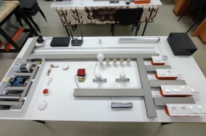 Stół z rozłożonym zestawem elementów instalacji elektrycznej, w tym żarówka, włączniki, przewody, gniazda i moduły sterujące w Zespole Szkół Technicznych w Cieszynie.
