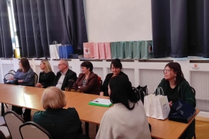 Współorganizatorzy i zaproszeni goście siedzą przy stole.
