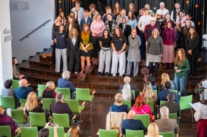 Występy artystyczne podczas jubileuszu 80-lecia LO im. Pawła Stalmacha. Na scenie stoi grupa uczniów i osób dorosłych podczas uroczystości jubileuszowej. W tle widoczna jest czarna kurtyna z dekoracją z liści oraz napisem „80 lat. Przystań i wspomnij”. Przed sceną siedzi publiczność na zielonych krzesłach.