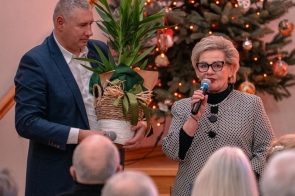 Beata Macura przemawia do mikrofonu. W tle siedzą uczestnicy spotkania, skierowani w stronę mówców.