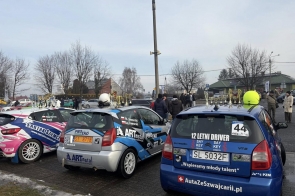 Kilka samochodów rajdowych zaparkowanych obok siebie, na dachach ustawione liczne puchary, a wokół zgromadzeni ludzie oglądający pojazdy. WOŚP w Powiecie Cieszyńskim Moto WOŚP w Skoczowie.