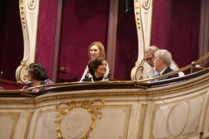 Kilka dorosłych osób siedzi w ozdobnej loży z białymi i złotymi zdobieniami. Wśród nich znajduje się m.in. Janina Żagan  Starosta Cieszyński, a obok niej Stanisław Kubicius Przewodniczący Rady oraz Katarzyna Stefka Naczelnik Wydziału Rady, Zarządu i Zdrowia. W tle widoczne są bordowe ściany i drzwi, a osoby w loży rozmawiają ze sobą i patrzą w różnych kierunkach.