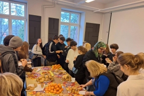 Uczestnicy konferencji dla uczniów stoją przy stołach z poczęstunkiem.