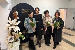 Cztery kobiety stoją obok siebie, od lewej: Lilla Salachna-Brzoza Przewodnicząca Komisji Rewizyjnej, Kornelia Zubek Dyrektor ZSGH w Wiśle, Danuta Łabaj Przewodnicząca Komisji Edukacji oraz Janina Żagan Starosta Cieszyński, trzymają bukiety kwiatów. W tle czarna ścianka z napisem „ZSG” i dekoracja kwiatowa.