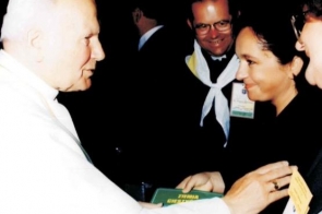 Jan Paweł II w białych szatach rozmawia z dwiema kobietami. W tle stoi mężczyzna.