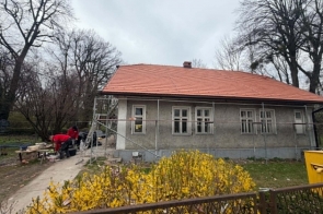 Remontowany budynek. Przed obiektem znajduje się zagospodarowany teren z roślinnością.