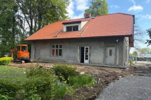 Remontowany budynek  Przed obiektem znajduje się zagospodarowany teren z roślinnością, ścieżkami oraz elementami małej architektury.