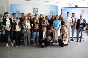 Grupa wyróżnionych osób pozuje do zdjęcia podczas gali sportu, trzymając dyplomy, statuetki i słoneczniki. W tle widać baner z herbem Powiatu Cieszyńskiego oraz ekran z napisem „Gala Sportu”.