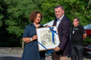 Janina Żagan Starosta Cieszyński i Tomasz Bujok Burmistrz Miasta Wisła pozują z oprawionym rysunkiem przedstawiającym Rotundę św. Mikołaja w Cieszynie, ozdobioną niebieską wstążką.