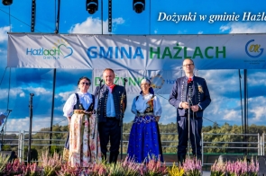 Scena podczas dożynek w gminie Hażlach. Na scenie stoją cztw=ery osoby w regionalnych strojach.