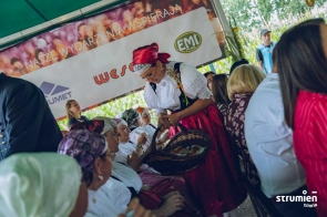 Poczęstunek dożynkowy. Kobieta z koszem dzieli przysmakami w gminie Strumień. 