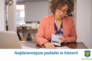 Kobieta w okularach i eleganckim stroju siedzi przy biurku, trzymając kalkulator i przeglądając dokumenty. Na dole widoczny napis „Najdziwniejsze podatki w historii” oraz herb Powiatu Cieszyńskiego.