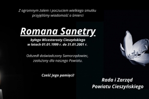 Plansza kondolencyjna z informacją o śmierci Romana Sanetry, byłego wicestarosty Powiatu Cieszyńskiego. Po lewej stronie widoczne zapalone świece, po prawej biały kwiat na ciemnym tle. Na dole podpis: Rada i Zarząd Powiatu Cieszyńskiego.