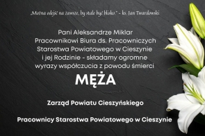 Tekst kondolencyjny na ciemnym tle z białą lilią, zawierający wyrazy współczucia z powodu śmierci męża skierowane do pracownicy starostwa i jej rodziny.