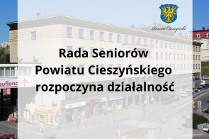 Widoczny jest budynek Starostwa Powiatowego w Cieszynie z główną ulicą i pieszymi na pierwszym planie. Na półprzezroczystym tle umieszczono napis: „Rada Seniorów Powiatu Cieszyńskiego rozpoczyna działalność”.