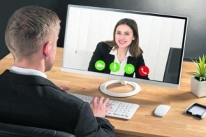 Po lewej znajduje się tył sylwetki mężczyzny, ubranego w garnitur, który ma ręce na klawiaturze, i rozmawia przez internet z uśmiechniętą, elegancko ubraną kobietą w młodym wieku.