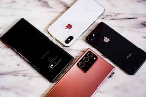 Cztery smartfony różnych marek na marmurowym tle: dwa iPhone’y (biały i czarny) oraz dwa Samsungi (czarny i różowe złoto). Urządzenia wyróżniają się stylowym designem i różnymi układami aparatów.