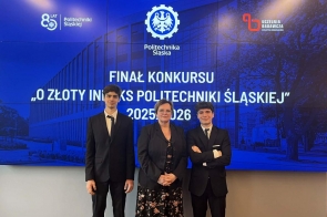Trzy osoby stoją przed ekranem z napisem o finale konkursu Politechniki Śląskiej. Dwóch mężczyzn w garniturach po bokach, Regina Rakowska Dyrektor II LO im.Mikołaja Kopernika pośrodku.