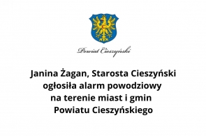 Grafika informacyjna z herbem Powiatu Cieszyńskiego i tekstem: "Janina Żagan, Starosta Cieszyński ogłosiła alarm powodziowy na terenie miast i gmin Powiatu Cieszyńskiego."