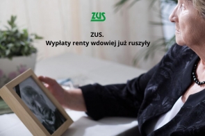 Starsza kobieta w eleganckim stroju siedzi przy stole i patrzy na czarno-białe zdjęcie mężczyzny w ramce, trzymając je w dłoni. Obok logo ZUS i napis „ZUS. Wypłaty renty wdowiej już ruszyły”.