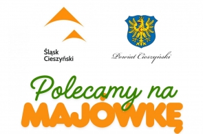 Grafika promocyjna majowego weekendu na Śląsku Cieszyńskim. W górnej części znajdują się dwa logotypy: po lewej znak „Śląsk Cieszyński” w kolorze pomarańczowym, po prawej herb Powiatu Cieszyńskiego – złoty orzeł na niebieskim tle – oraz napis „Powiat Cieszyński”. W centralnej części tekst: „Polecamy na MAJÓWKĘ”