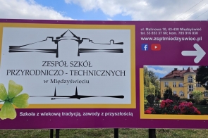 Grafika promocyjna Szkoły w Zespołu Szkół Przyrodniczo-Technicznych w Międzyświeciu na bordowym tle z mapą i małym zdjęciem budynku.