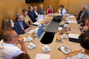 arada poświęcona bezpieczeństwu w Powiecie Cieszyńskim. Przy dużym stole konferencyjnym siedzą przedstawiciele służb, inspekcji, straży oraz samorządu. Uczestnicy mają przed sobą dokumenty i notatki, trwa rozmowa i wymiana informacji.