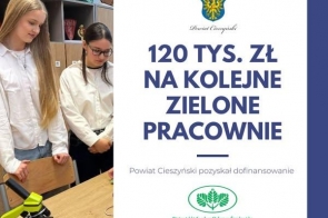 Dwie uczennice stoją przy stole i przyglądają się mikroskopowi. Obok znajduje się część z herbem Powiatu Cieszyńskiego i dużym napisem o dofinansowaniu na zielone pracownie oraz logo instytucji na dole.