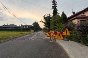 Droga asfaltowa oznaczona znakami drogowymi informującymi o remoncie i utrudnieniach w ruchu.