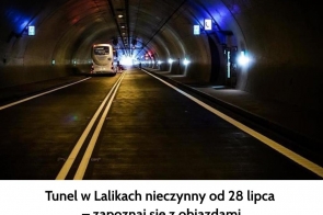 Wnętrze oświetlonego tunelu drogowego z wyraźnym podziałem pasów ruchu. W oddali porusza się biały autokar, przed którym widać jasne światło wyjazdu. Po bokach ścian znajdują się znaki informacyjne i punkty ewakuacyjne. Na dole grafiki widoczny jest napis informujący o zamknięciu tunelu w Lalikach i objazdach .