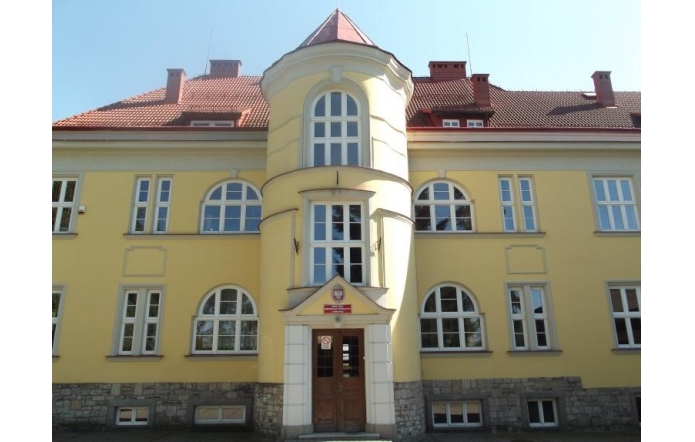  Budynek z jasną, żółtą elewacją i czerwonym, spadzistym dachem. Na środku fasady znajduje się charakterystyczna, zaokrąglona wieżyczka z dużymi, łukowatymi oknami. Wejście główne prowadzi przez drewniane drzwi z górnym naświetlem. Na budynku widoczna jest tablica informacyjna, że jest to Zespół Szkół Przyrodniczo-Technicznych w Międzyświeciu.