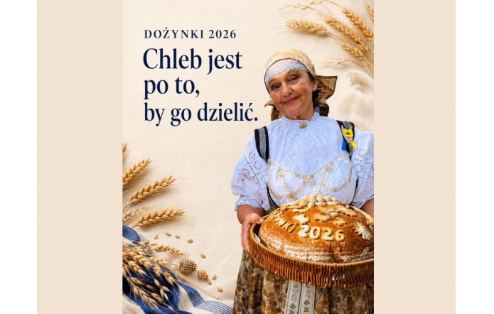 Beżowa grafika dożynkowa z kłosami zbóż i napisem „Dożynki 2026. Chleb jest po to, by go dzielić.” Po prawej stronie stoi Janina Żagan Starosta Cieszyńska w stroju regionalnym, trzymająca w wiklinowym koszu duży, ozdobny bochen chleba z napisem „Dożynki 2026”.