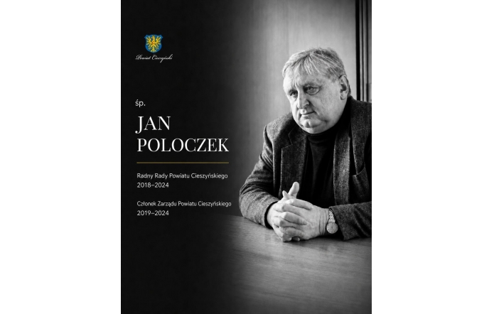 Jan Poloczek siedzi przy stole, lekko pochylony, ze splecionymi dłońmi. Ma na sobie golf i marynarkę. Z poważną, zamyśloną twarzą patrzy w bok. Po lewej stronie widnieją herb Powiatu Cieszyńskiego, jego imię i nazwisko oraz pełniona funkcja.