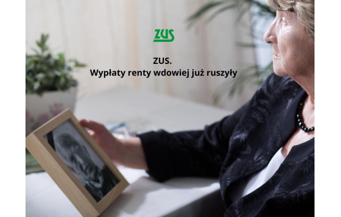 Starsza kobieta w eleganckim stroju siedzi przy stole i patrzy na czarno-białe zdjęcie mężczyzny w ramce, trzymając je w dłoni. Obok logo ZUS i napis „ZUS. Wypłaty renty wdowiej już ruszyły”.