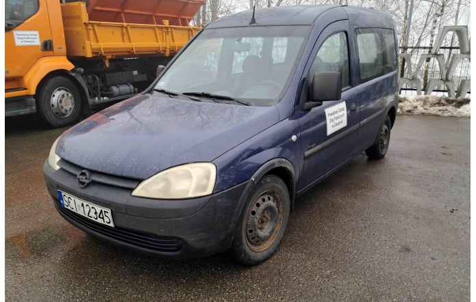 Opel Combo z oznaczeniem Powiatowego Zarządu Dróg Publicznych w Cieszynie, zaparkowany na mokrej nawierzchni obok pojazdu ciężarowego.