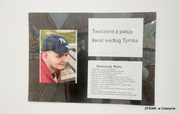 Tablica prezentuje portret młodego mężczyzny w czapce z daszkiem oraz tekst zatytułowany „Tworzone z pasją – świat według Tymka”. Poniżej umieszczono opis opowiadający o osobie, jej życiu i twórczości. W tle widać delikatne motywy artystyczne, co podkreśla kreatywność autora. Całość sprawia wrażenie hołdu złożonego pasji i talentowi.